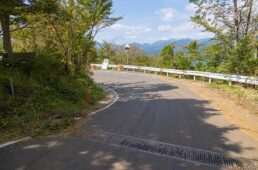 下りの注意ポイント①：菜の花台前。道を横切るグレーチング（溝を覆う格子状のふた）はハンドルを取られやすいから気をつけなくてはならないものの、そればかりを気にすると対向車に気づくのが遅れてしまう。カーブの先にある菜の花台に出入りする車は道路中央に寄っていることも多く、いざという場合も安全に避けられるよう、十分に減速してからカーブに入ろう。