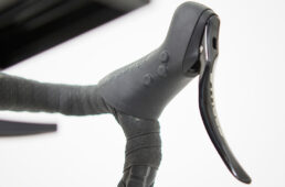 シフトレバーはステージズオリジナル。一般的なロード用のシフターのようにブレーキレバーの横に変速スイッチがなく、ブラケットの内側にある3つのボタンと、下ハンにある2つのスプリンタースイッチで変速操作などを行う。