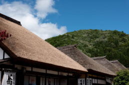 青空と茅葺き屋根と緑の山々