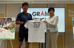 ポロシャツを小池知事から手渡される武井さん