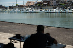 漁港内の漁船を見ながら昼飯にかぶりつくシシャチョー
