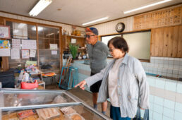 魚屋でオススメを確認するお母さん