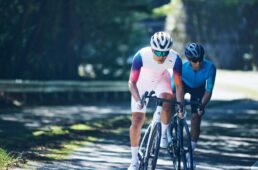 夏用ウェアを着用して木漏れ日の中を走る2人のサイクリスト